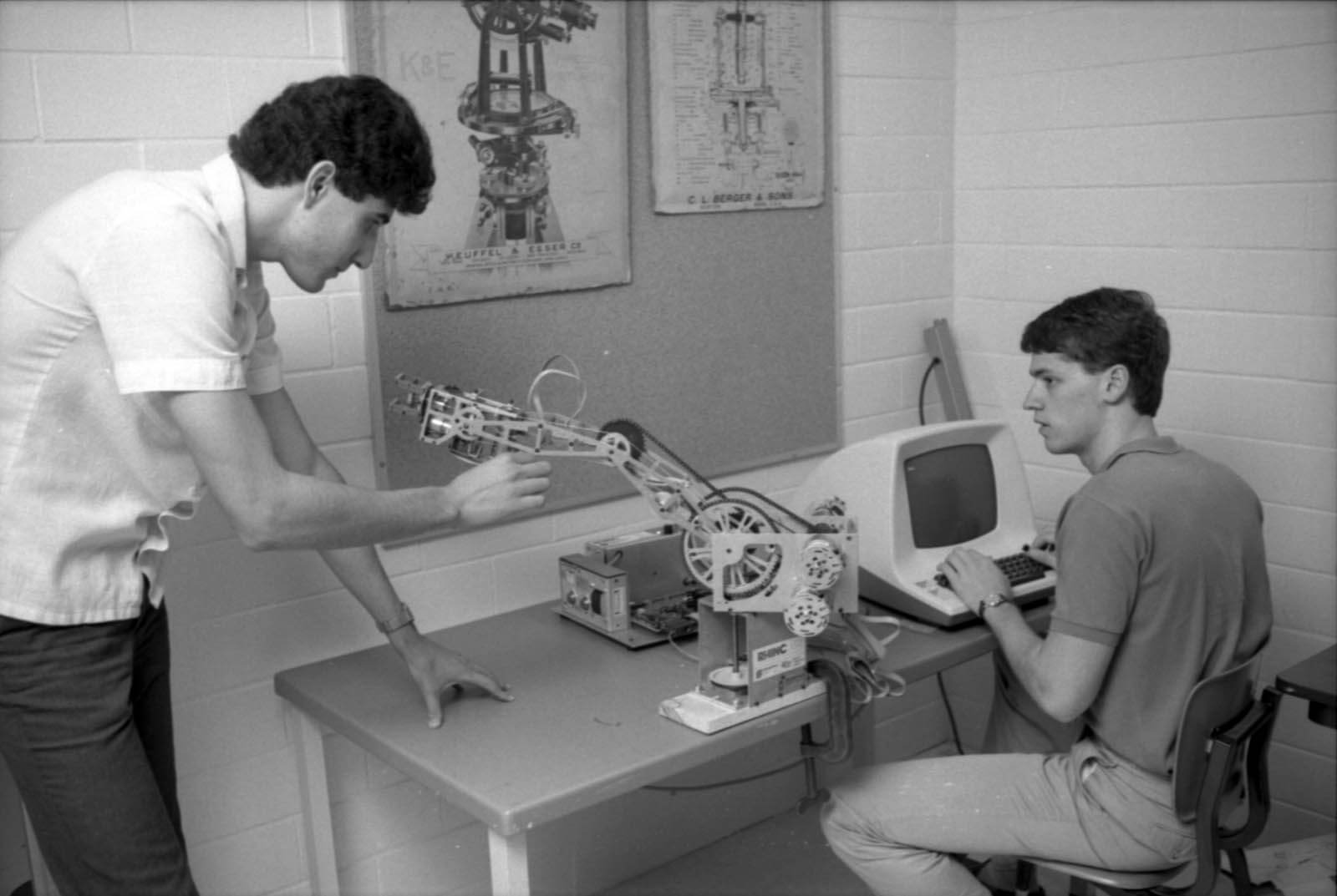 Vintage photo of two students working on a robotic arm