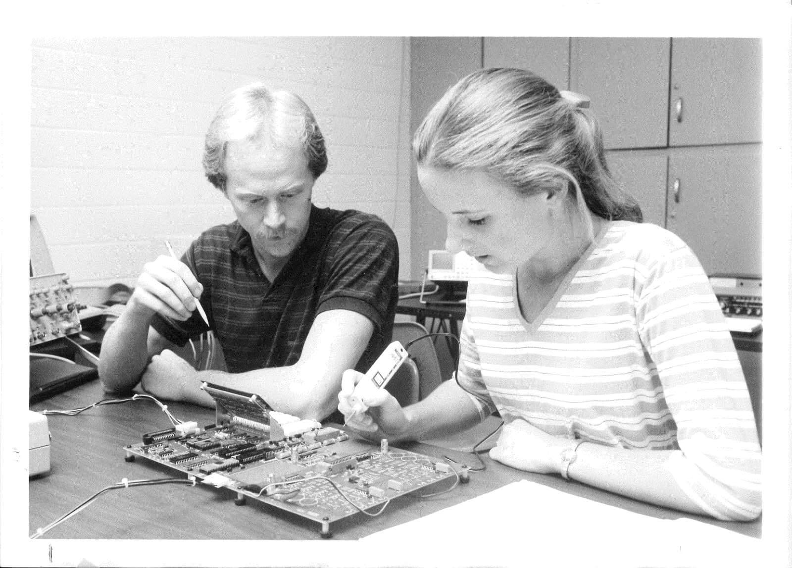 Vintage photo of two students working on a circuit board