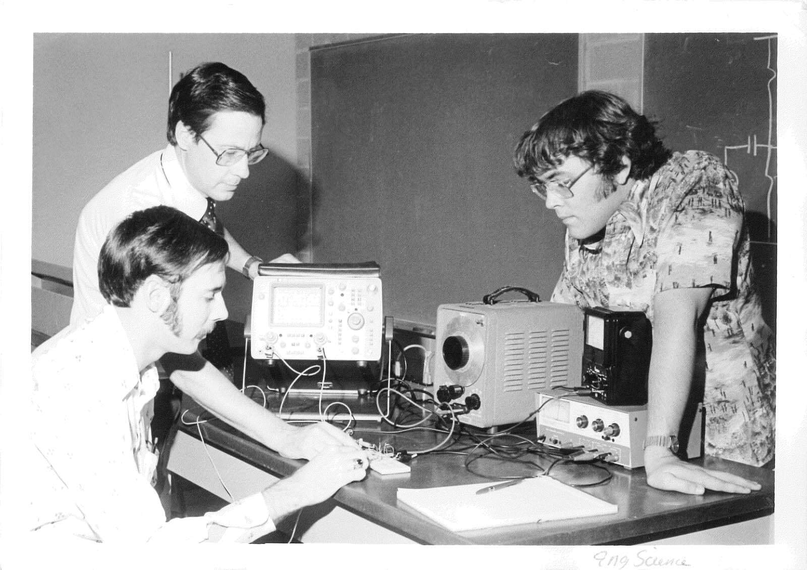 Vintage photo of a professor and students working on a piece of equipment