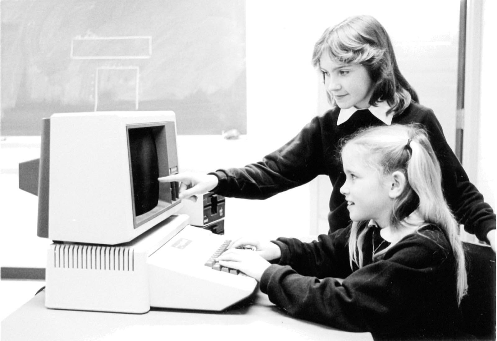A vintage photo of young students working at a computer