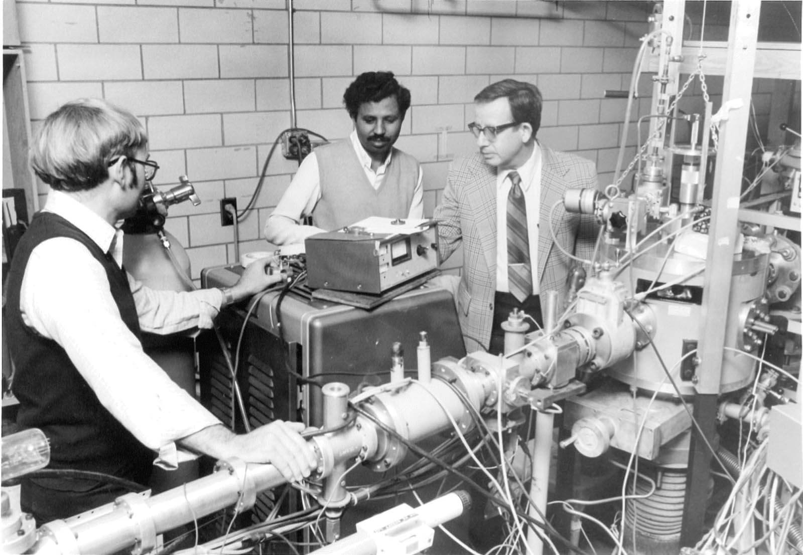 A vintage photo of a researcher and students working with a piece of equipment