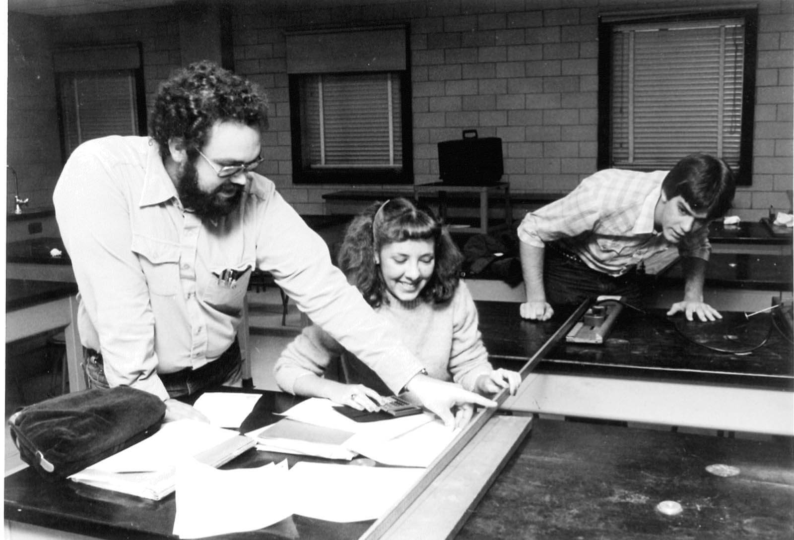 A vintage photo of a researcher and students working with a piece of equipment